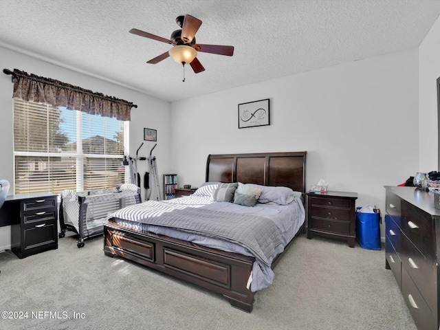 bedroom with ceiling fan, light colored carpet, and a textured ceiling