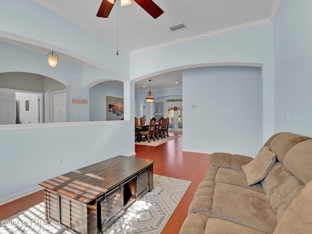 living room with hardwood / wood-style flooring, ceiling fan, ornamental molding, and a textured ceiling