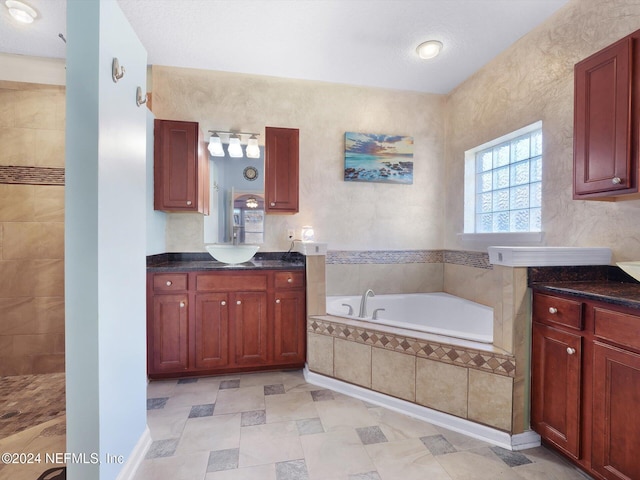 bathroom with vanity, a relaxing tiled tub, and a textured ceiling