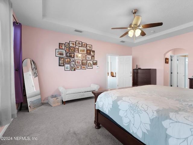 carpeted bedroom with a tray ceiling and ceiling fan