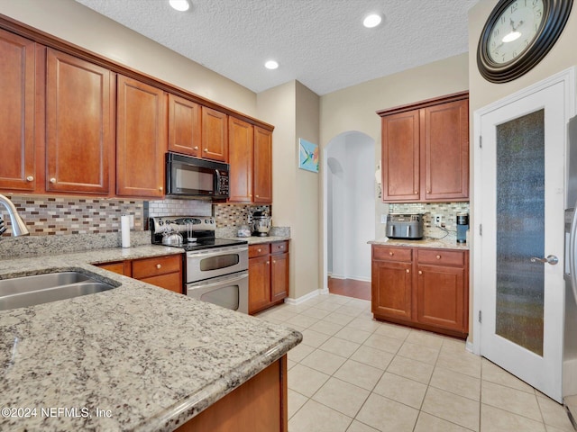 kitchen featuring light tile patterned floors, a textured ceiling, double oven range, and sink