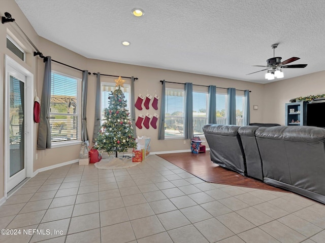 living room featuring plenty of natural light, ceiling fan, light tile patterned floors, and a textured ceiling