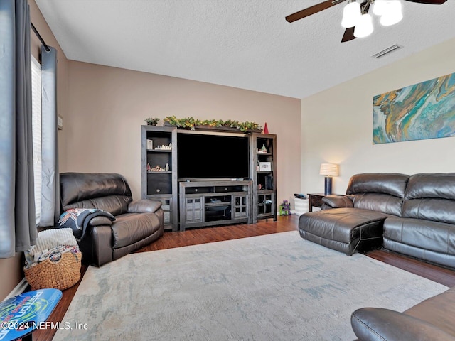 living room featuring a textured ceiling, dark hardwood / wood-style flooring, and ceiling fan