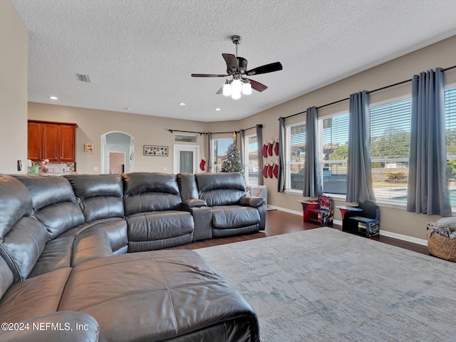 living room featuring a textured ceiling, dark hardwood / wood-style flooring, and ceiling fan