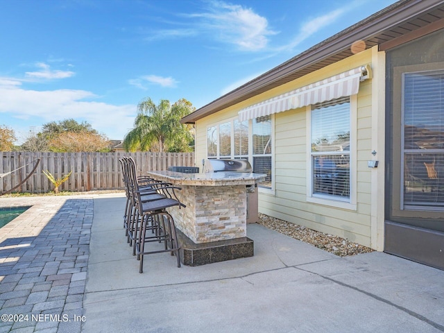 view of patio with exterior bar, area for grilling, and a grill