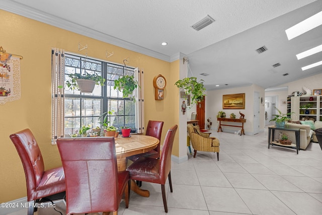 dining space featuring light tile patterned floors, a textured ceiling, lofted ceiling with skylight, and crown molding