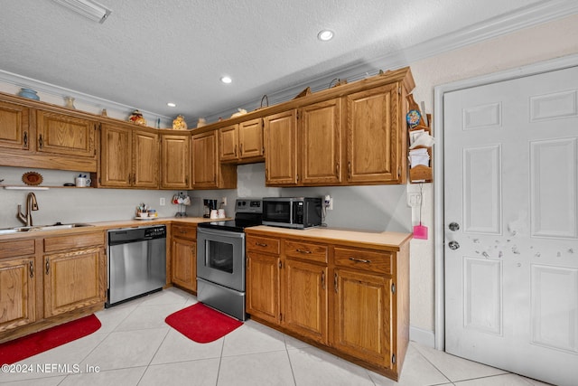 kitchen with a textured ceiling, light tile patterned flooring, sink, and appliances with stainless steel finishes