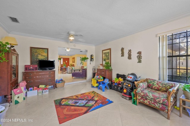 playroom with ceiling fan, light tile patterned floors, a textured ceiling, and ornamental molding