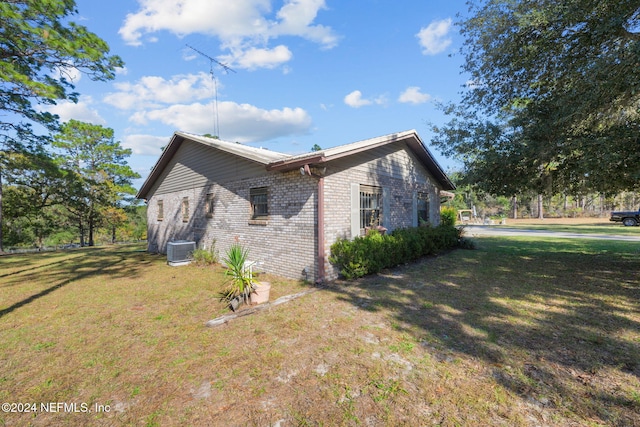 view of home's exterior with a lawn and central AC