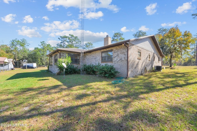 view of side of property with a yard and central AC