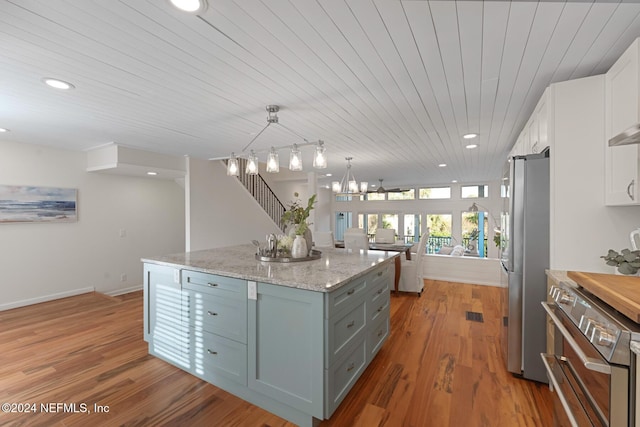 kitchen featuring stainless steel appliances, a kitchen island, pendant lighting, light hardwood / wood-style floors, and white cabinetry