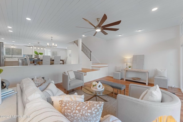 living room featuring ceiling fan with notable chandelier, light hardwood / wood-style floors, and wood ceiling