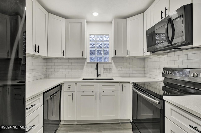 kitchen with backsplash, white cabinetry, sink, and black appliances