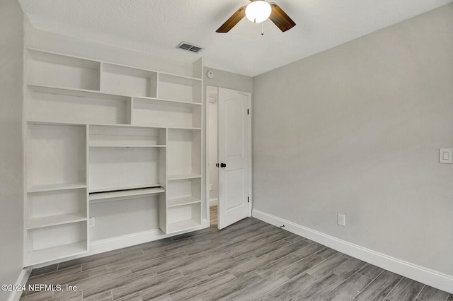 unfurnished bedroom featuring hardwood / wood-style floors, a textured ceiling, ceiling fan, and a closet