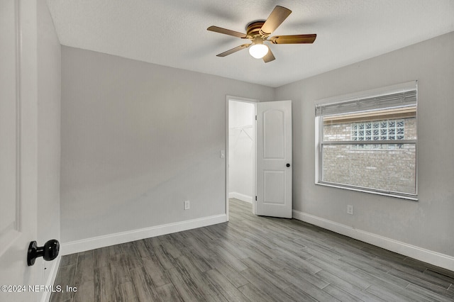 unfurnished room with ceiling fan, a textured ceiling, and light wood-type flooring