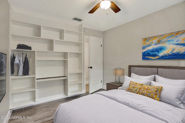 bedroom featuring hardwood / wood-style flooring, ceiling fan, and a textured ceiling