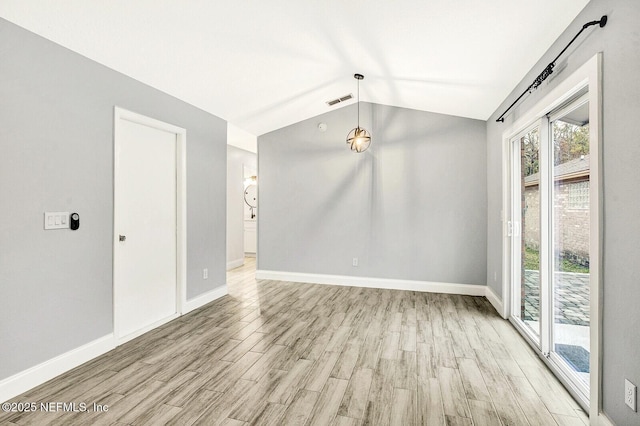 spare room with light hardwood / wood-style floors and lofted ceiling