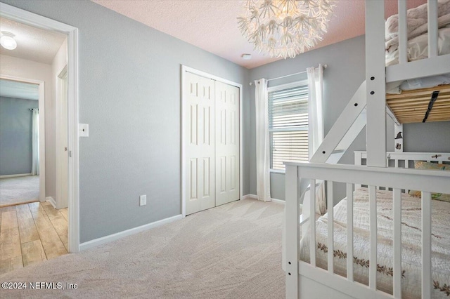 carpeted bedroom with a closet, a chandelier, and a textured ceiling