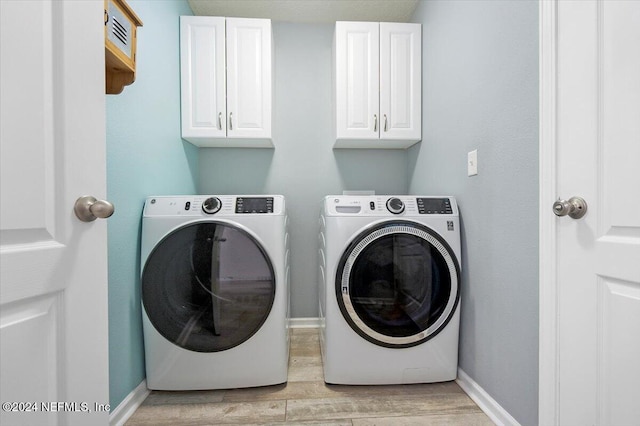 laundry room featuring cabinets, washer and dryer, and light wood-type flooring