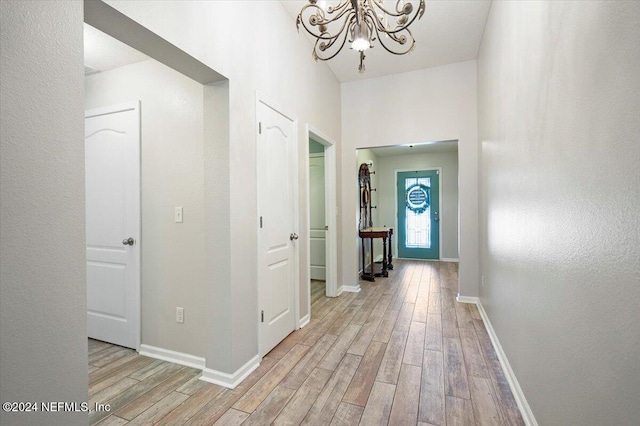 hall with light hardwood / wood-style flooring and an inviting chandelier