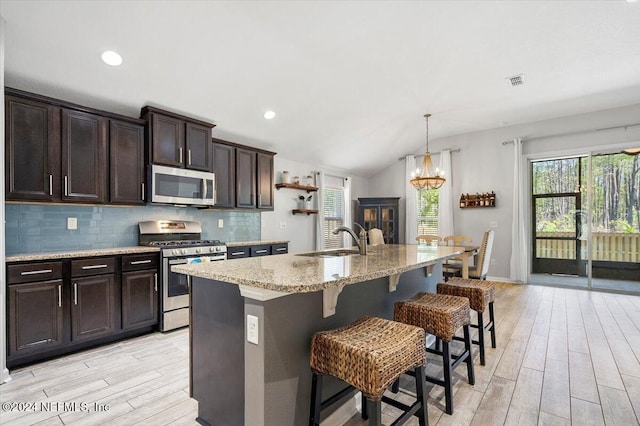 kitchen featuring lofted ceiling, sink, light hardwood / wood-style flooring, an island with sink, and appliances with stainless steel finishes