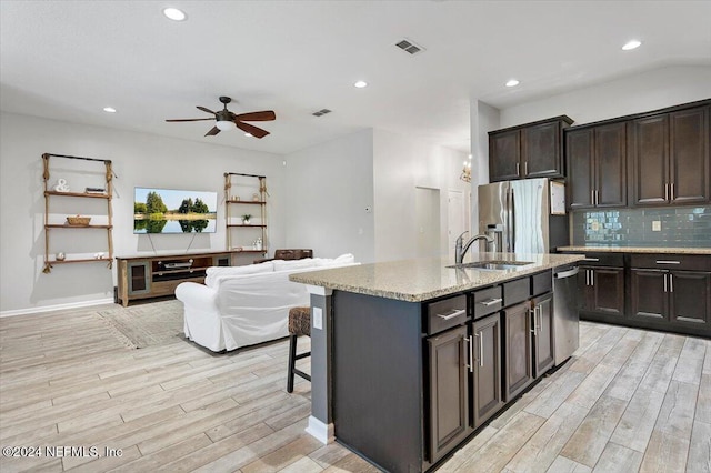 kitchen featuring ceiling fan, sink, stainless steel appliances, an island with sink, and light hardwood / wood-style floors