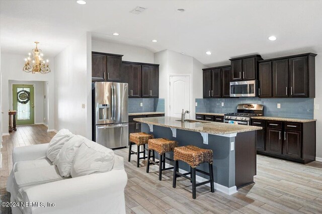 kitchen featuring sink, stainless steel appliances, a kitchen breakfast bar, light hardwood / wood-style flooring, and an island with sink