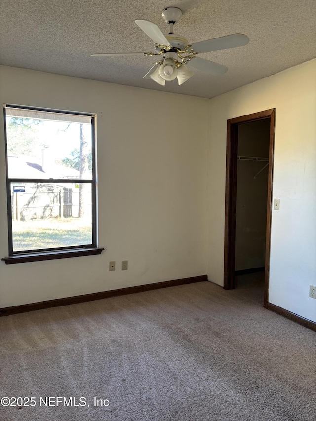 carpeted empty room featuring ceiling fan and a textured ceiling