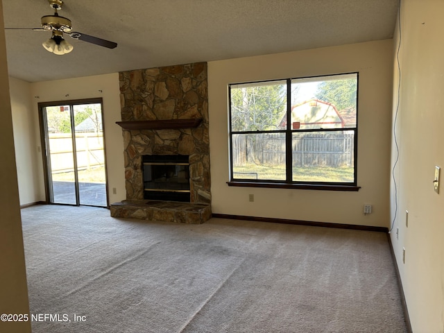 unfurnished living room featuring a textured ceiling, ceiling fan, a stone fireplace, and light carpet