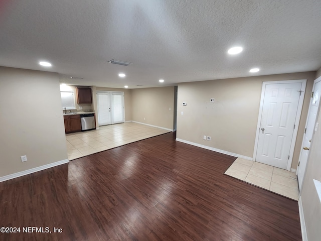 unfurnished living room with sink, light wood-type flooring, and a textured ceiling