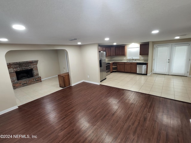 unfurnished living room featuring a fireplace, a textured ceiling, light wood-type flooring, and sink