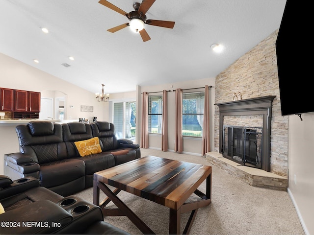 carpeted living room with ceiling fan with notable chandelier, vaulted ceiling, and a stone fireplace