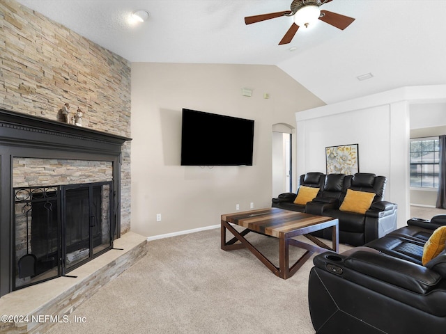 carpeted living room featuring a stone fireplace, ceiling fan, and vaulted ceiling