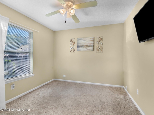 spare room featuring carpet flooring, ceiling fan, and a textured ceiling