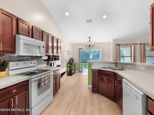 kitchen featuring hanging light fixtures, an inviting chandelier, light hardwood / wood-style flooring, lofted ceiling, and white appliances