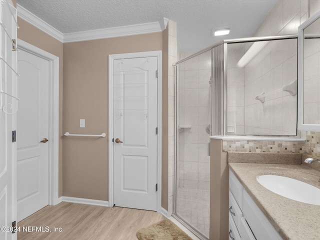 bathroom featuring wood-type flooring, a textured ceiling, an enclosed shower, and crown molding