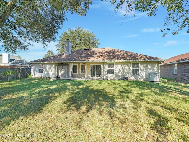 rear view of house with central AC and a yard