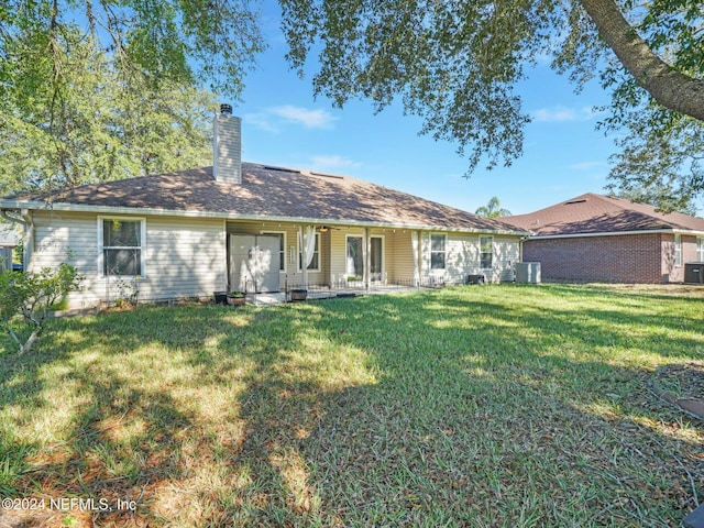 rear view of house featuring a lawn and central AC unit