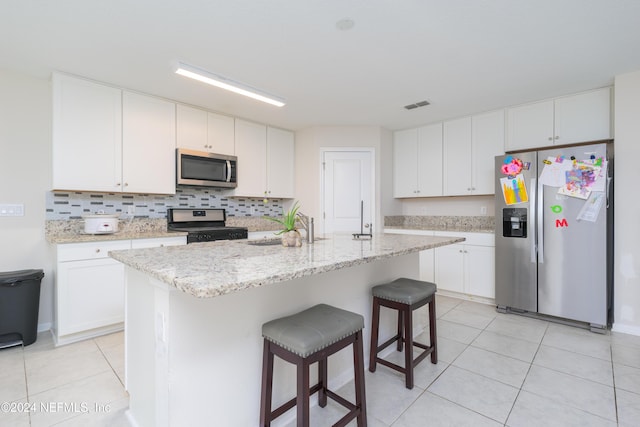 kitchen with white cabinets, stainless steel appliances, and an island with sink