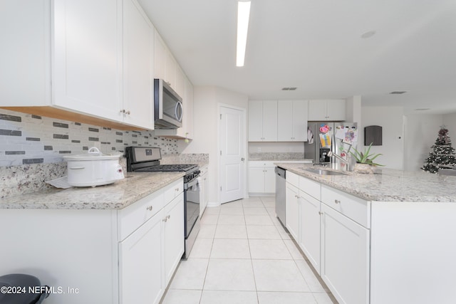 kitchen featuring decorative backsplash, stainless steel appliances, sink, light tile patterned floors, and white cabinetry