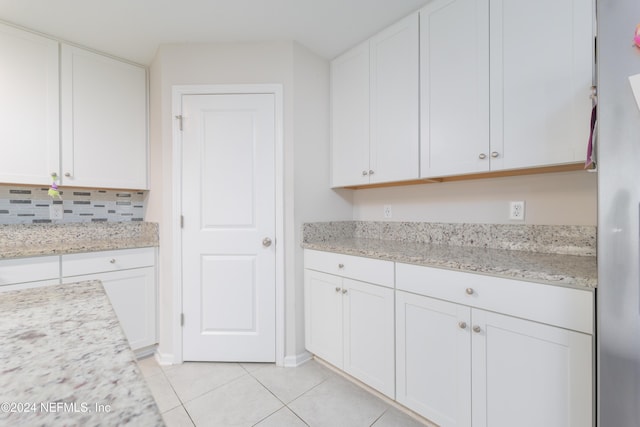 kitchen with white cabinetry, light tile patterned floors, and light stone counters