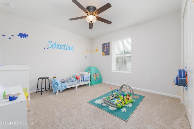 bedroom featuring ceiling fan, carpet floors, and a nursery area