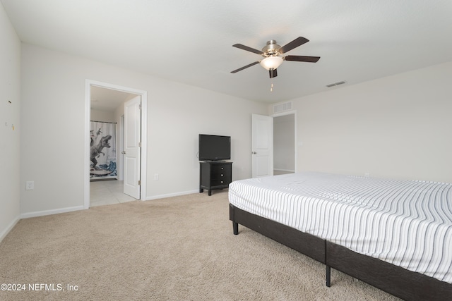 carpeted bedroom with ensuite bathroom and ceiling fan