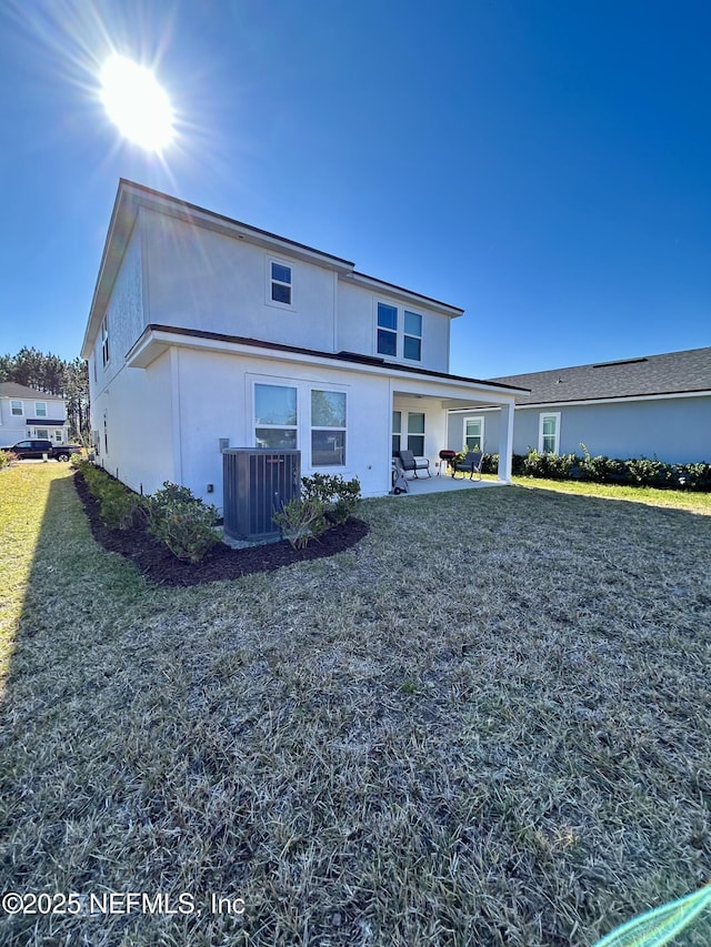 view of front of house with a front yard, central AC unit, a patio area, and stucco siding