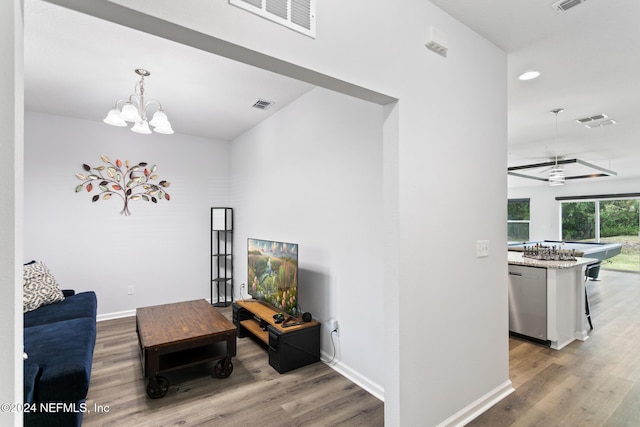 living room with hardwood / wood-style floors and ceiling fan with notable chandelier