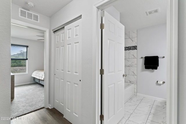 bathroom with tiled shower / bath combo and a textured ceiling