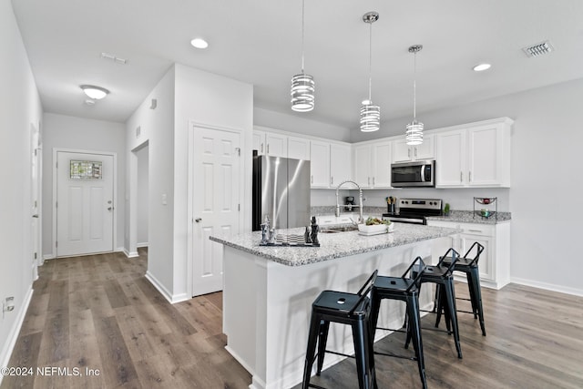 kitchen featuring white cabinets, stainless steel appliances, and a center island with sink