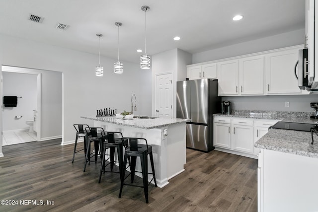 kitchen featuring a kitchen island with sink, dark hardwood / wood-style flooring, white cabinets, and stainless steel appliances