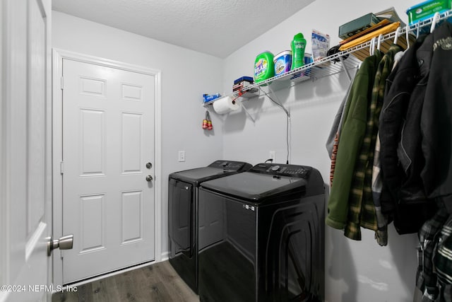 clothes washing area featuring washer and clothes dryer, wood-type flooring, and a textured ceiling