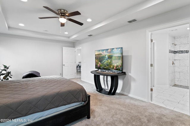 carpeted bedroom featuring connected bathroom, a tray ceiling, and ceiling fan